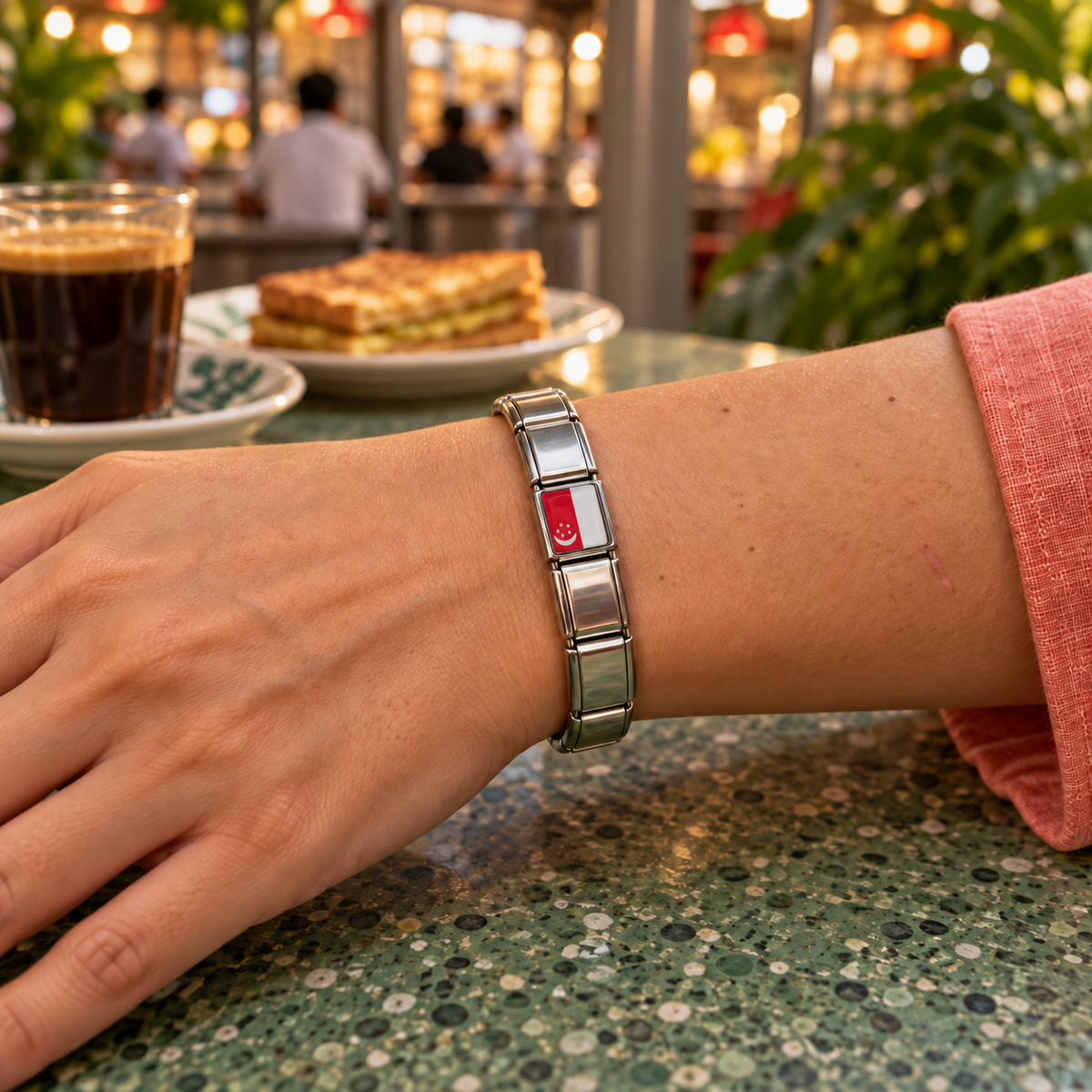 Singapore flag Italian charm on an Italian charm bracelet worn at a lively hawker centre with kopi and kaya toast