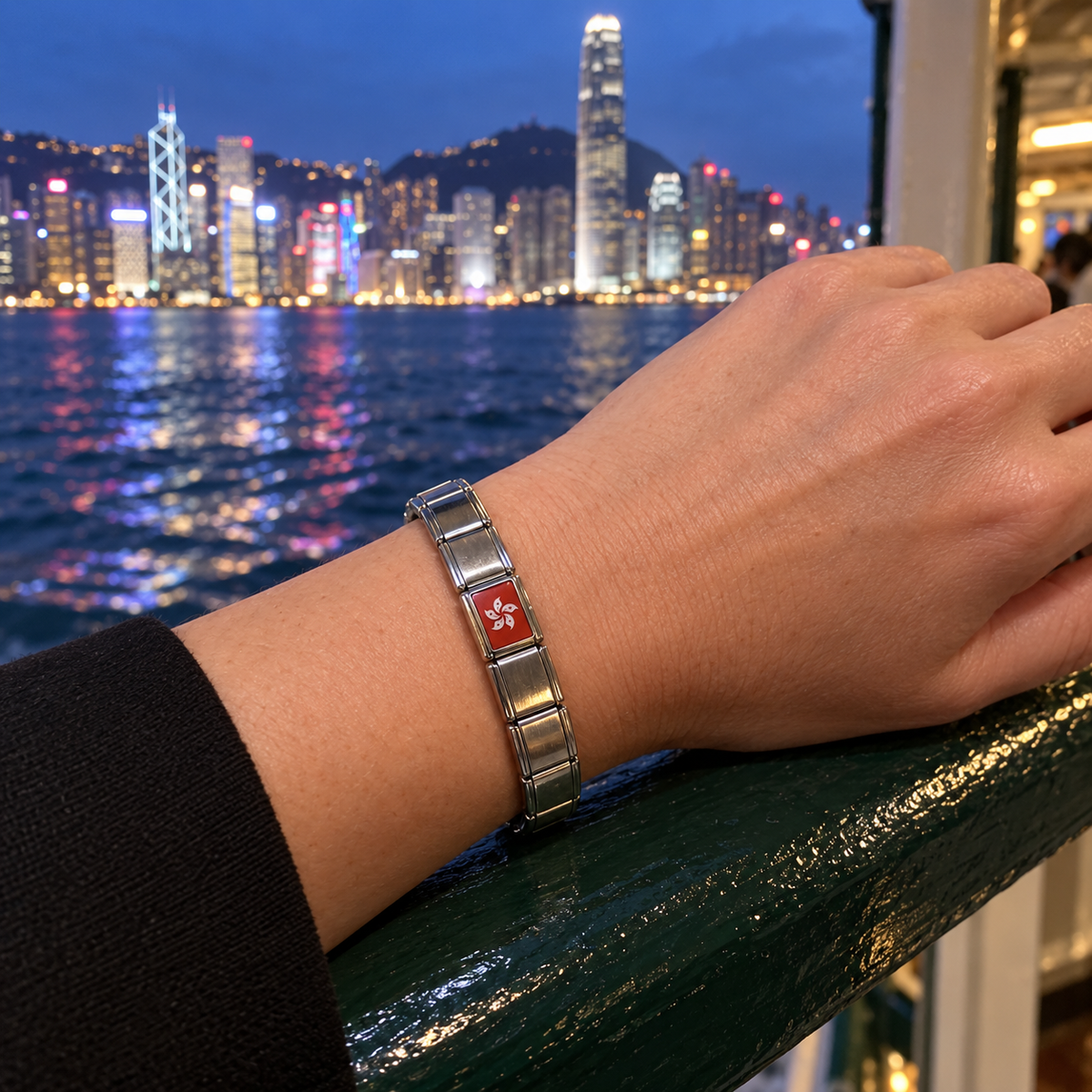Hong Kong flag Italian charm on a shiny silver charm bracelet overlooking Victoria Harbour at night
