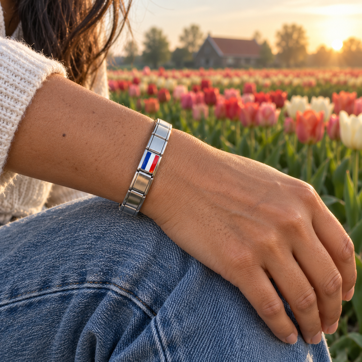 Netherlands flag charm on a polished silver charm bracelet beside colorful Dutch tulip fields
