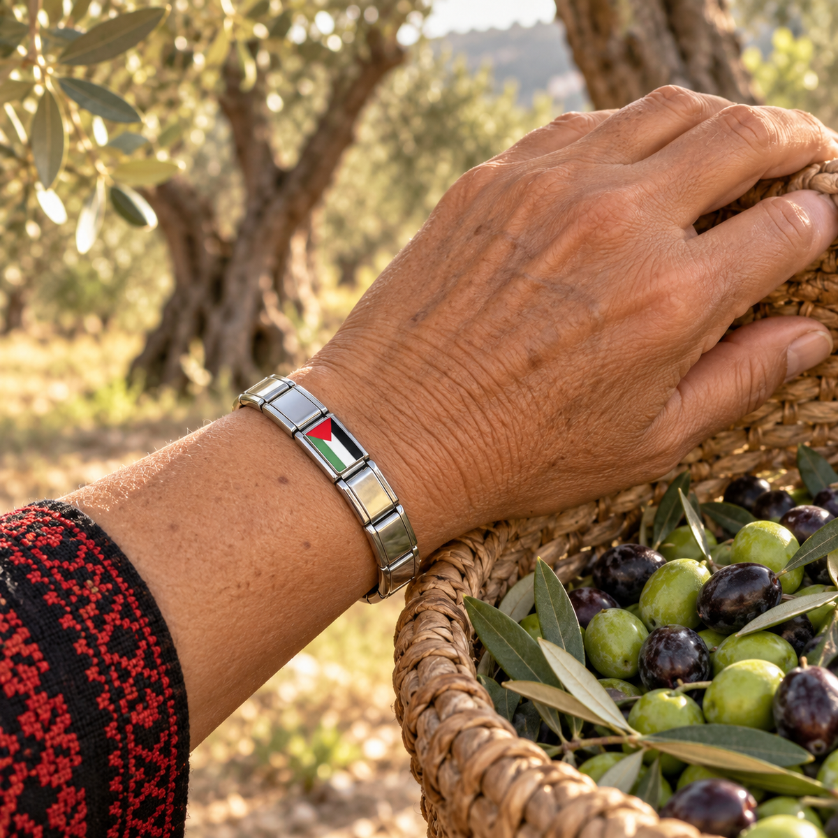Palestine flag Italian charm on a silver charm bracelet worn by a woman gathering olives in a sunlit olive grove