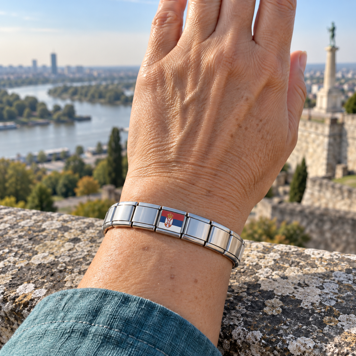 Serbia flag Italian charm on a shiny silver base bracelet worn at a Belgrade overlook near the Sava and Danube
